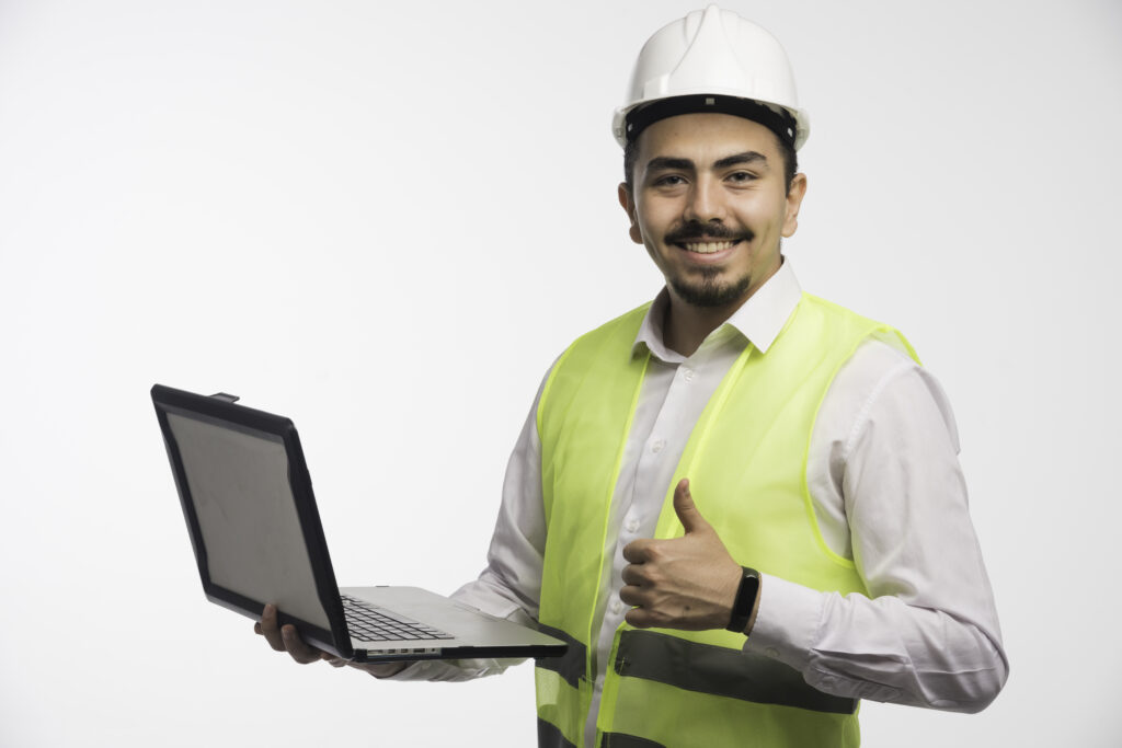 Engineer in uniform holding a laptop and making thumb up. High quality photo