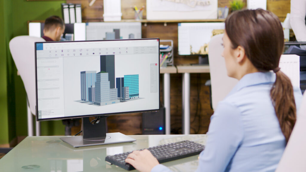 Female architect making 3d building models on computer. Architect holding blueprint.